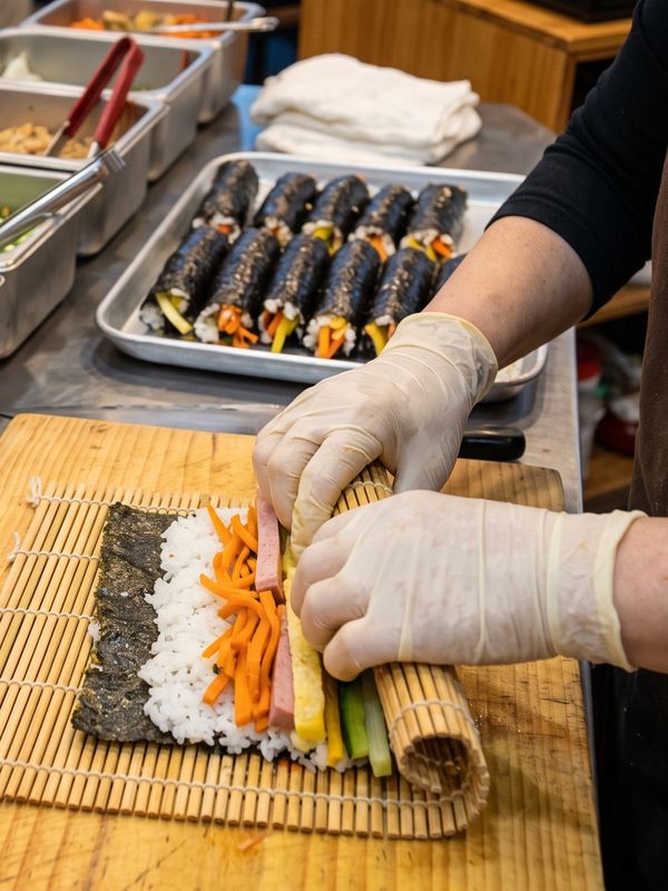 장갑 낀 손으로 김밥을 마는 모습(AI 연출 이미지)
